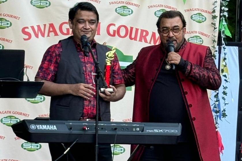 Ali A.Z (left) holds a trophy on stage at an outdoor event. Photo supplied by Ali A.Z.